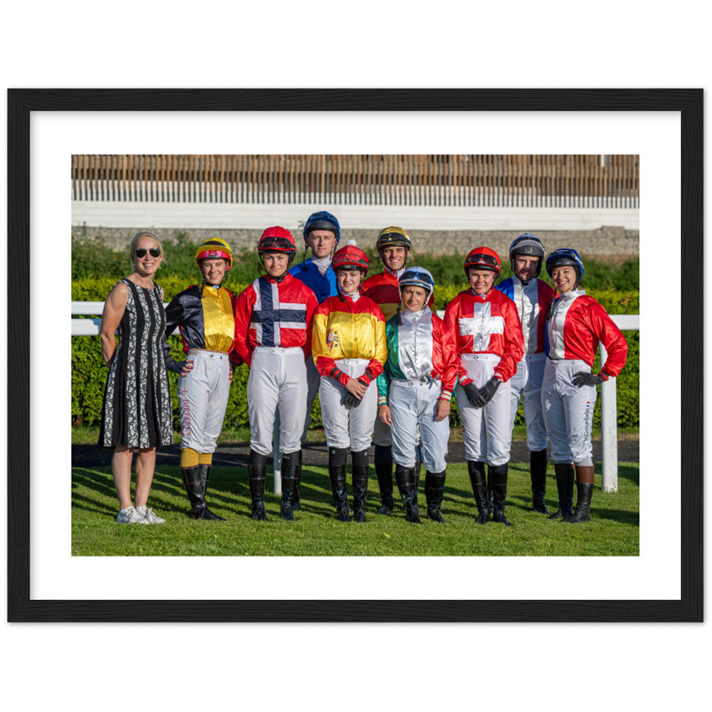 Ryttere i fargerike jockeydrakter står i en gruppe på en hestebane, med en kvinne i svart kjole til venstre. Grønn bakgrunn.